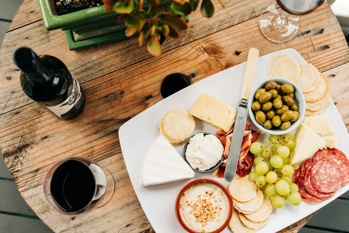 A board of cheese, olives, charcuterie and red wine