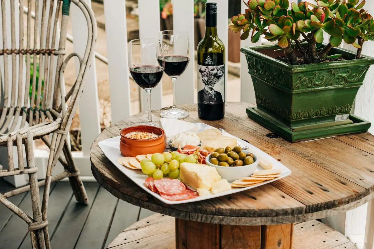 Glasses of red wine and a charcuterie plate on a terrace table